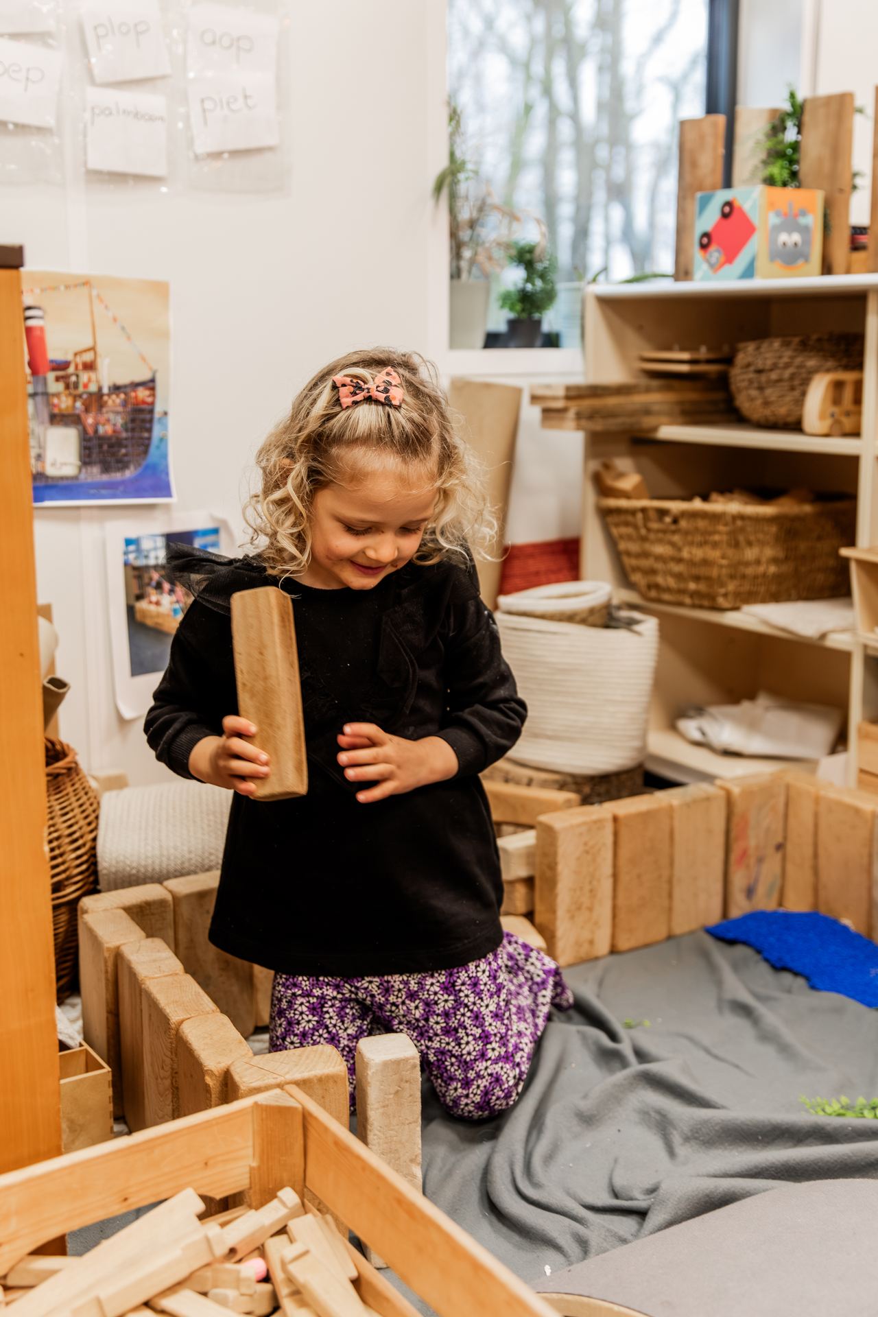 Een meisje bouwt met houten blokken in de bouwhoek