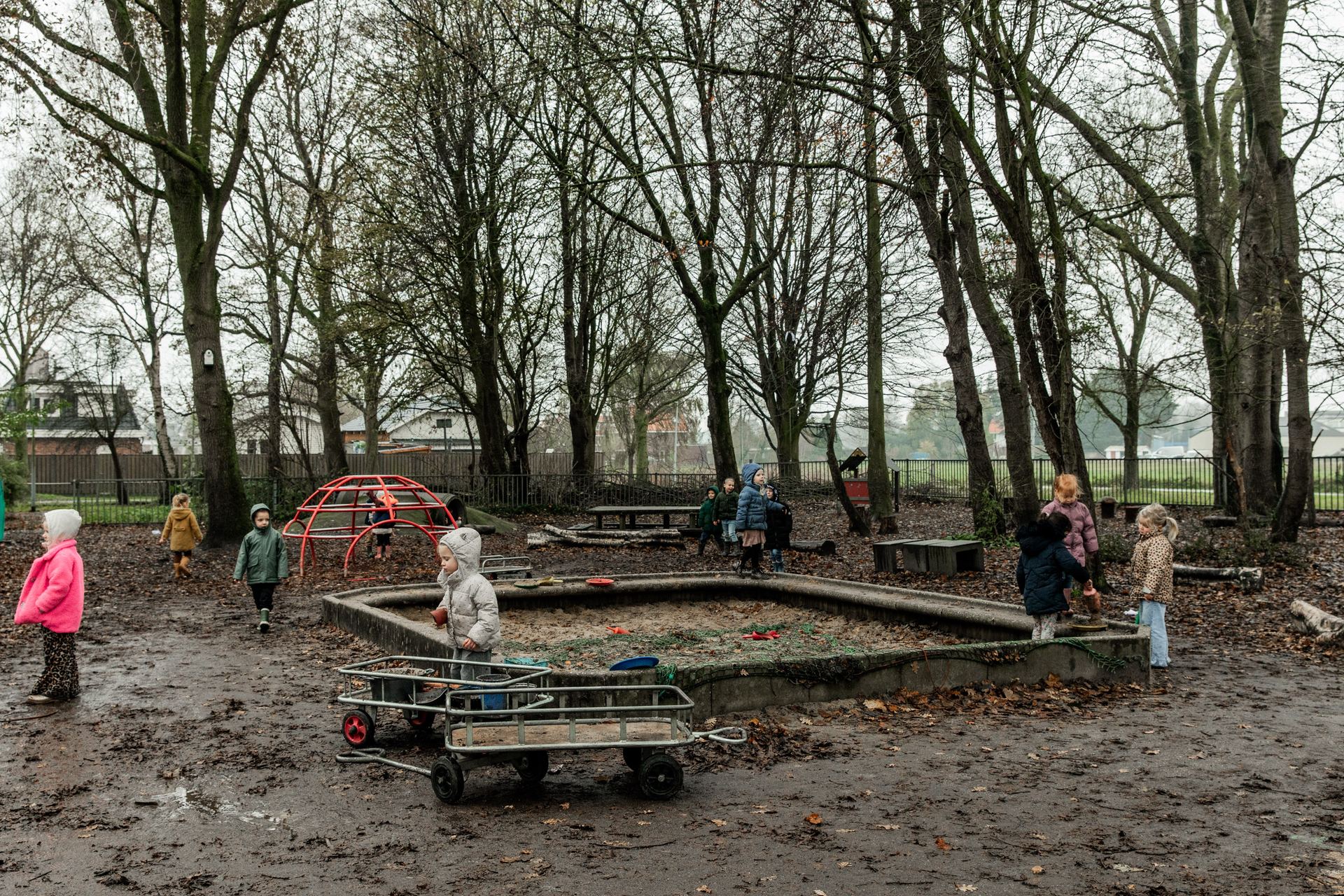 De buitenspeelplaats met bolderkarren en speelgoed tussen de bomen