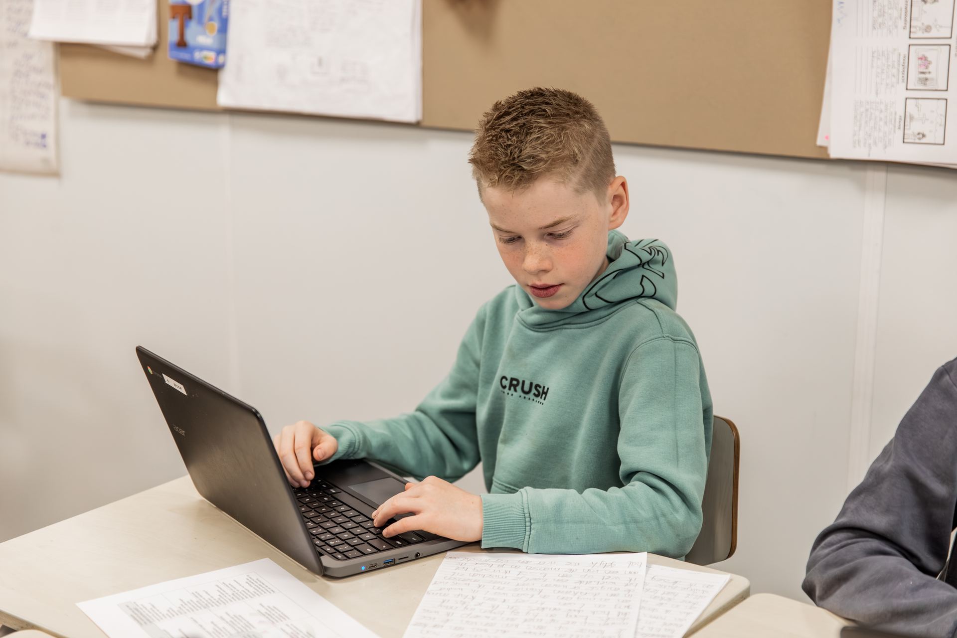 Een jongen werkt geconcentreerd op zijn chromebook