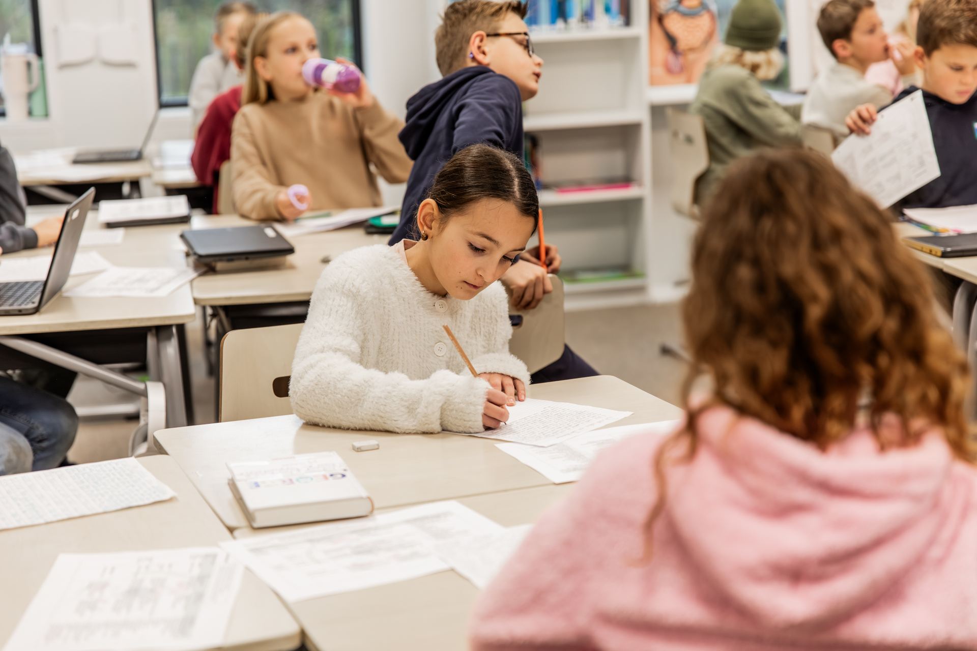 Leerlingen werken aan hun tafels in de klas
