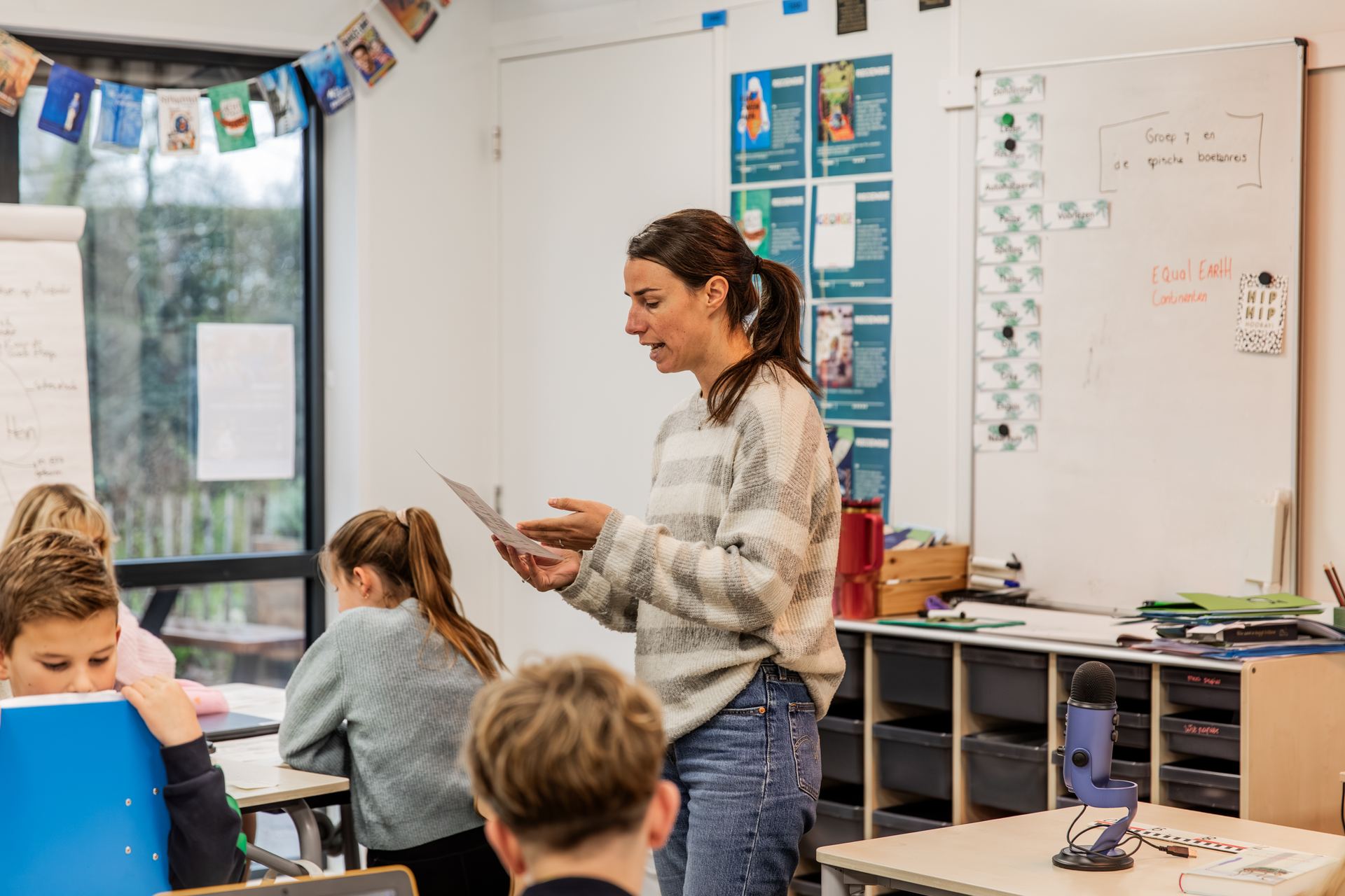 Een leerkracht deelt werkbladen uit in de klas