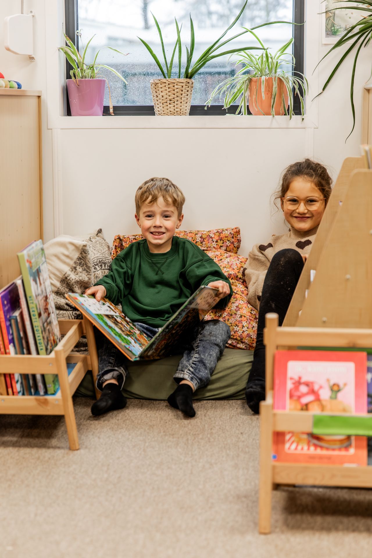 Twee kinderen lezen samen een boek in de leeshoek
