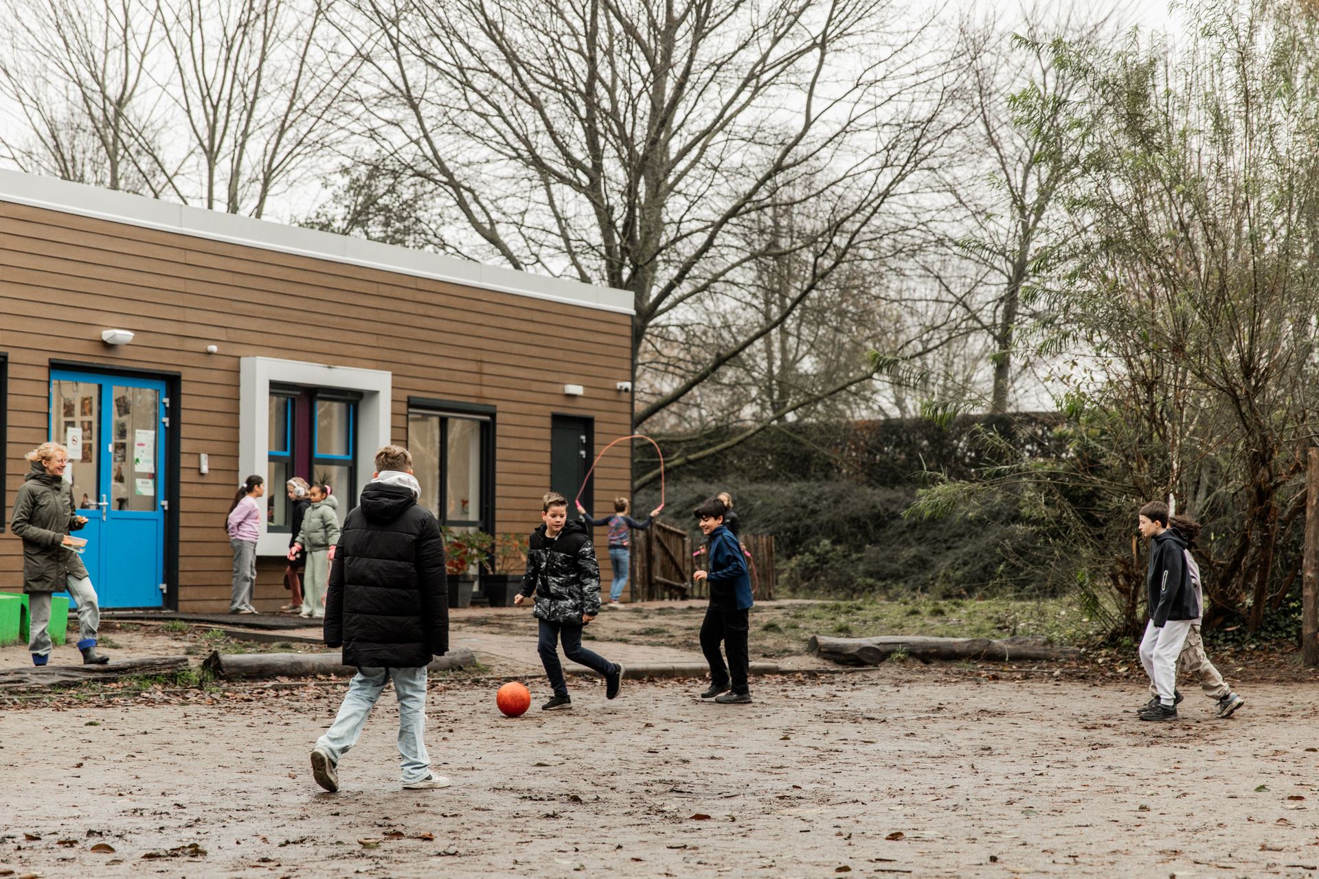 Kinderen spelen met een bal op het plein voor de school