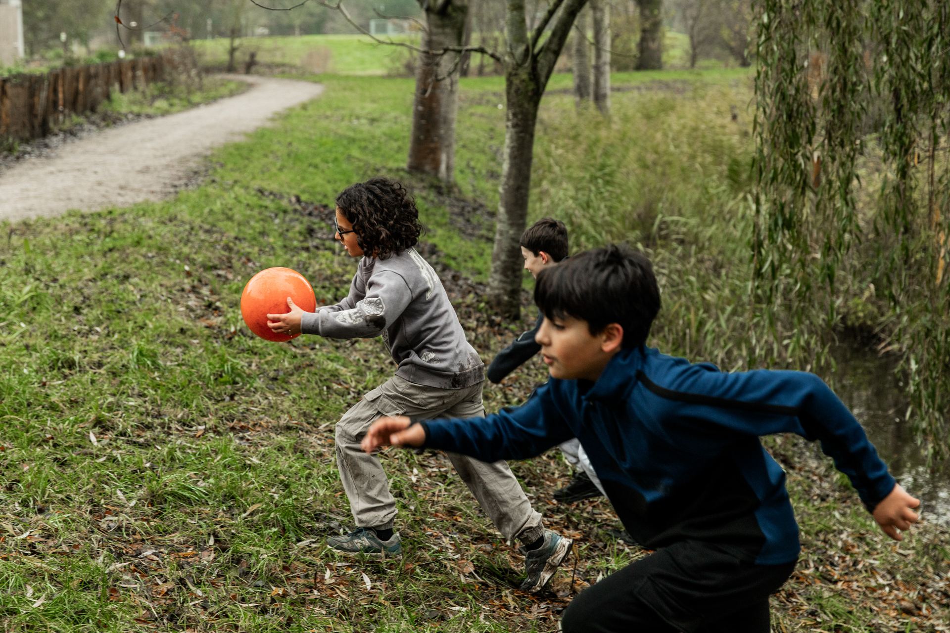 Twee jongens rennen met een bal over het gras