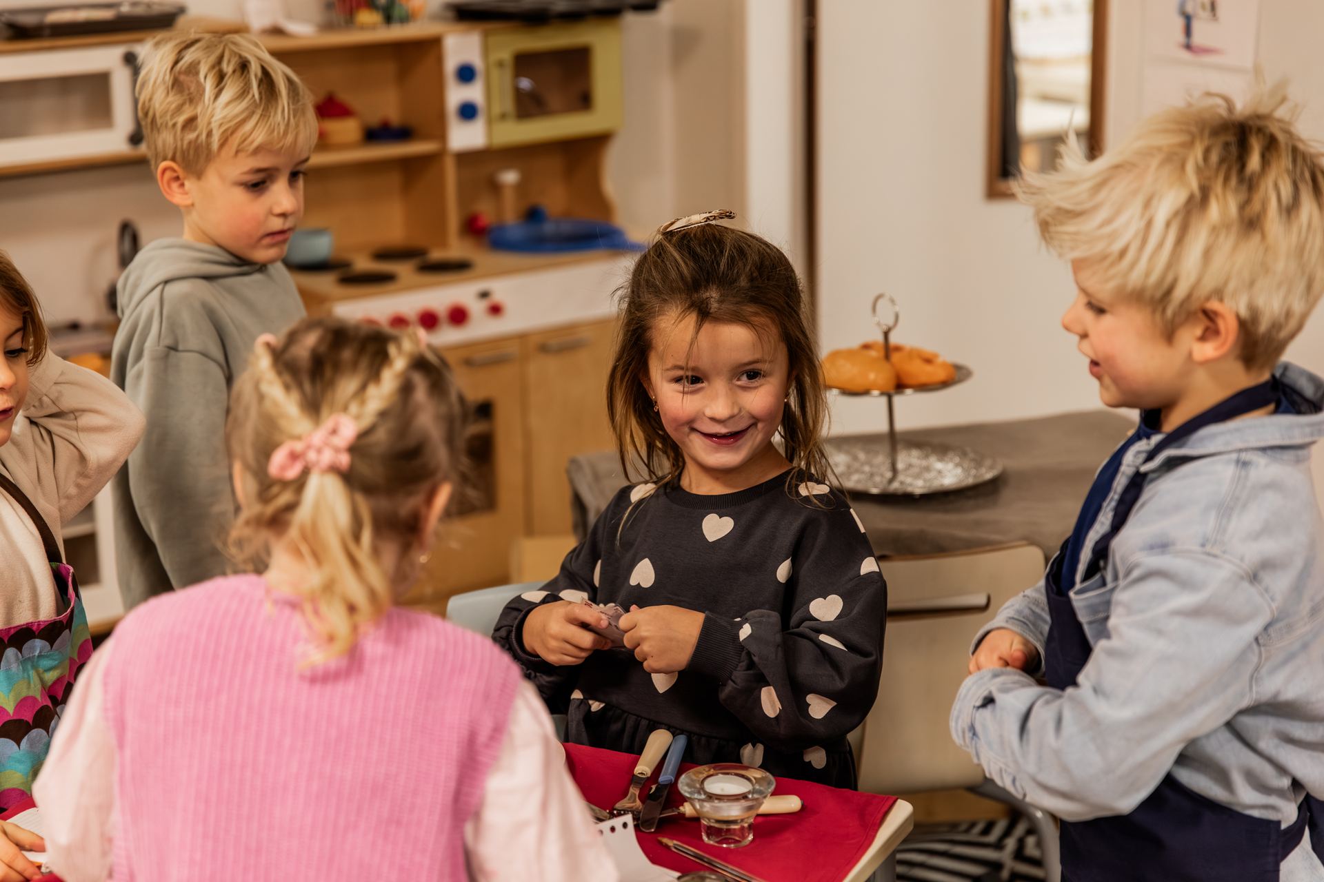 Kleuters spelen restaurant aan een tafel met een rood kleed